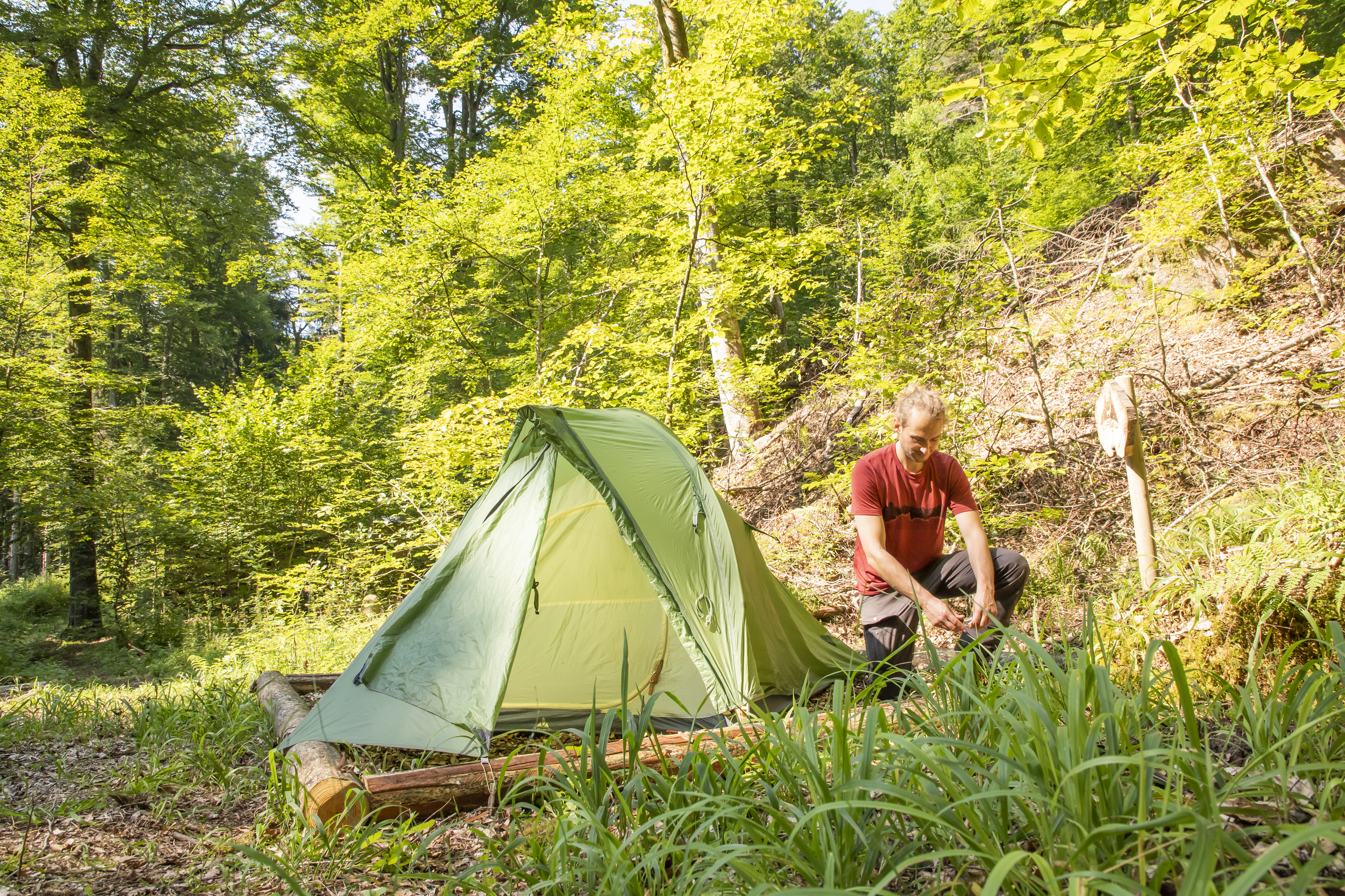 Trekking im Naturpark Neckartal-Odenwald (c) Stilfotografie Maren Kunkelmann Mann baut ein Zelt im Wald auf.